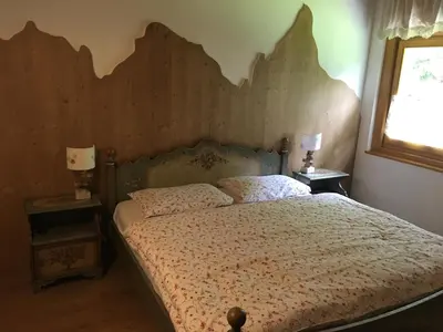 a bedroom with a bed with a wooden headboard at Villa La Brisa in Predazzo