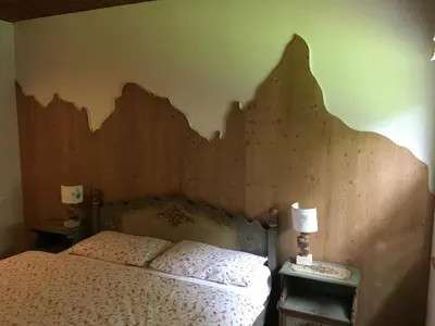 a bedroom with a bed with a wooden headboard at Villa La Brisa in Predazzo