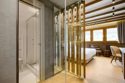 a hotel room with a bed and a glass corridor at Grand Hotel Savoia Cortina d'Ampezzo, A Radisson Collection Hotel in Cortina dʼAmpezzo