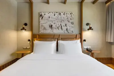 a bedroom with a large bed with two white pillows at Grand Hotel Savoia Cortina d'Ampezzo, A Radisson Collection Hotel in Cortina dʼAmpezzo