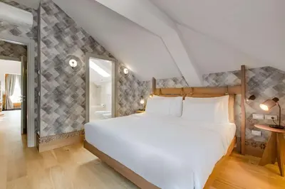 a bedroom with a white bed and a bathroom at Grand Hotel Savoia Cortina d'Ampezzo, A Radisson Collection Hotel in Cortina dʼAmpezzo