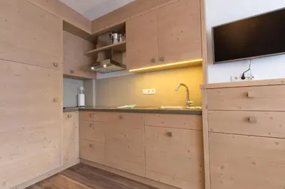 a kitchen with wooden cabinets and a flat screen tv at Apartments Ciasa Costa in Badia