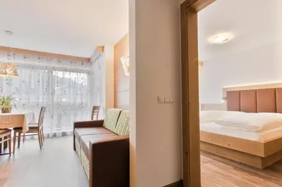 a bedroom with a bed and a dining room with a table at Apartments Ciasa Costa in Badia