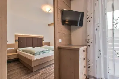 a bedroom with a bed and a tv on a wall at Apartments Ciasa Costa in Badia