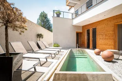 an outdoor patio with lounge chairs and a swimming pool at Hotel Valserhof in Valles