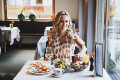 a woman sitting at a table with a plate of food at Hotel Valserhof in Valles