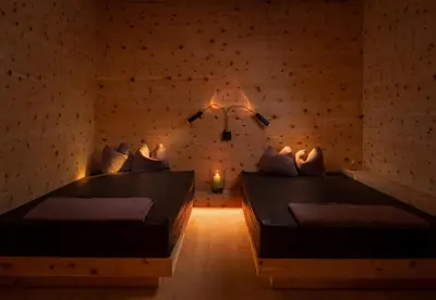 a room with two beds and a lamp on the wall at Hotel Valserhof in Valles