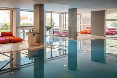 a pool in a building with a large room with windows at Hotel Valserhof in Valles