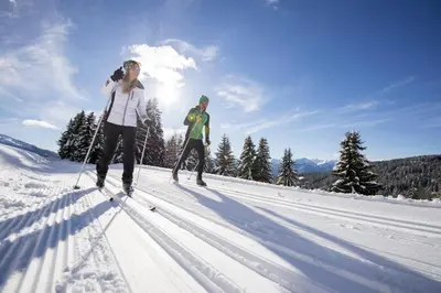 two people cross country skiing on a snow covered slope at Hotel Valserhof in Valles