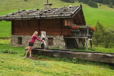a woman standing in front of a small house at Hotel Valserhof in Valles