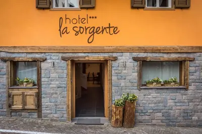 a building with two windows and a sign that reads hold la supreme at Hotel La Sorgente in Tesero