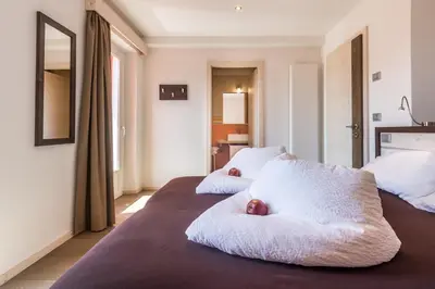 a bedroom with two beds with white sheets and two apples at Hotel La Sorgente in Tesero