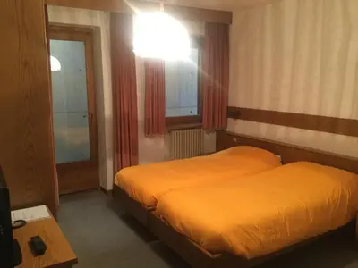 a hotel room with two beds and a light at Hotel Alpenrose in Alleghe