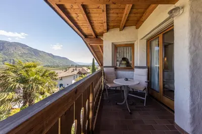 a balcony with a table and chairs and mountains at Die Villa bei Meran in Marlengo