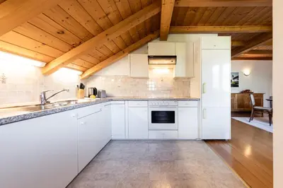 a kitchen with white cabinets and a wooden ceiling at Die Villa bei Meran in Marlengo