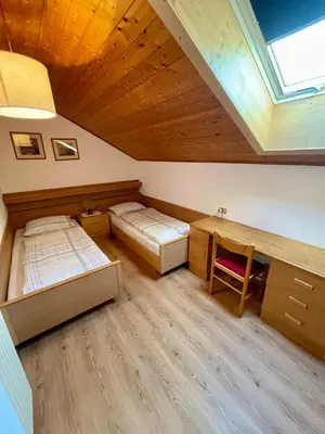 a attic bedroom with two beds and a desk at Gutshof Erschbaumer in San Lorenzo di Sebato