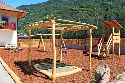 a playground with a wooden pergola and swings at Residence Egger in Terlano