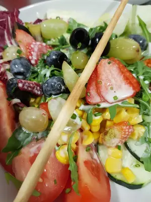 a salad with fruit and vegetables on a plate with chopsticks at Residence Egger in Terlano