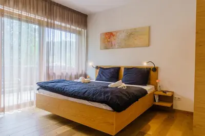 a bedroom with a bed with blue sheets and a window at Julias Guesthouse in Ora/Auer