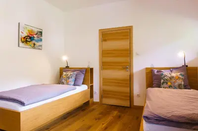 a bedroom with two beds and a door at Julias Guesthouse in Ora/Auer