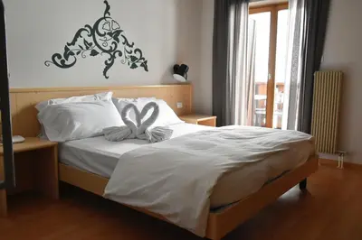 a bedroom with a bed with a bow on it at Hotel Principe Marmolada in Malga Ciapela