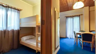 a bedroom with bunk beds and a dining room with a table at Hotel Principe Marmolada in Malga Ciapela