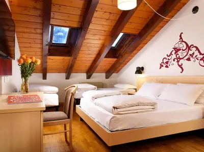 a bedroom with three beds and a table and a desk at Hotel Principe Marmolada in Malga Ciapela
