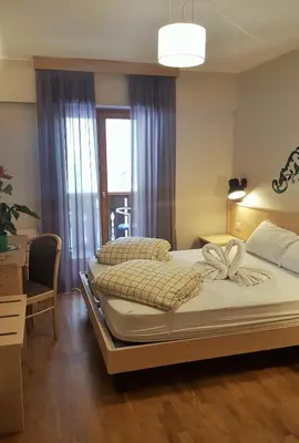 a bedroom with two beds and a desk and a window at Hotel Principe Marmolada in Malga Ciapela
