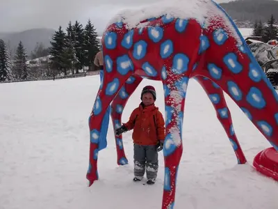 a young child standing in the snow next to a statue at Rosenheim in Maranza