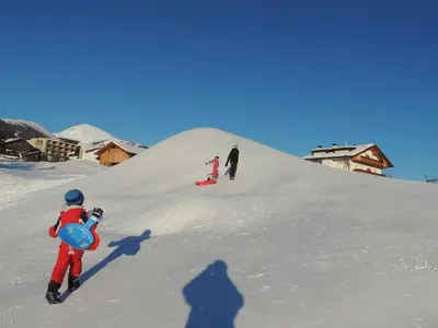 a group of people walking up a snow covered slope at Rosenheim in Maranza