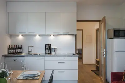 a kitchen with white cabinets and a wooden table at Weingut Messnerhof in Bolzano