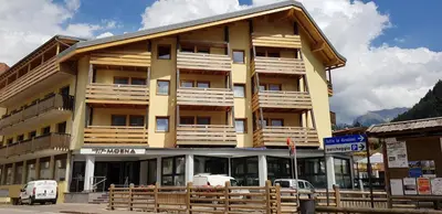 a yellow building with wooden balconies on a street at Hotel Moena in Moena