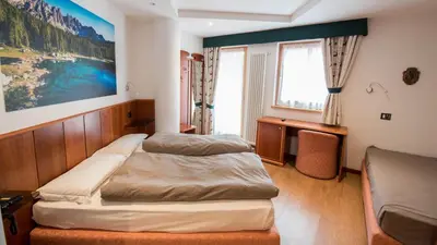 a bedroom with a bed and a painting on the wall at Hotel Moena in Moena