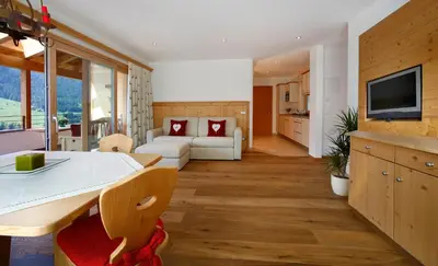 a kitchen and living room with a table and a couch at Apartments Victoria in Ortisei