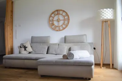 a living room with a couch and a clock on the wall at Hintnerhof in Chiusa