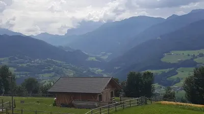 a small house on a hill with mountains in the background at Hintnerhof in Chiusa