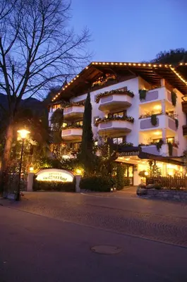 a large white building with lights on it at night at Hotel Sittnerhof in Merano