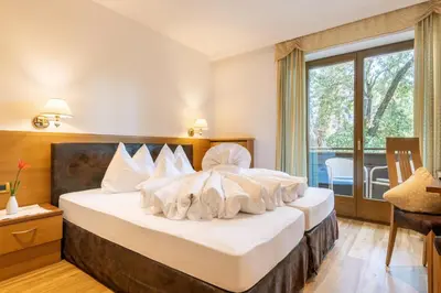 a bedroom with a large bed with white pillows at Hotel Sittnerhof in Merano