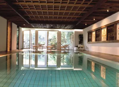 a swimming pool with tables and chairs in a house at Hotel Sittnerhof in Merano