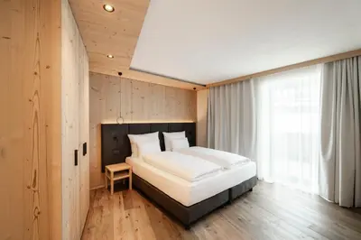 a bedroom with a large bed and a window at NEW OPENING LA TRUGA Suite Apartments in Selva di Val Gardena