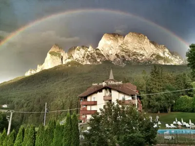 a rainbow over a building in front of a mountain at Parc Hotel Miramonti in Fiè