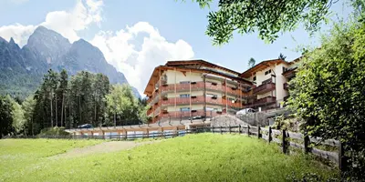 a building on a hill with a grassy field in front at Parc Hotel Miramonti in Fiè