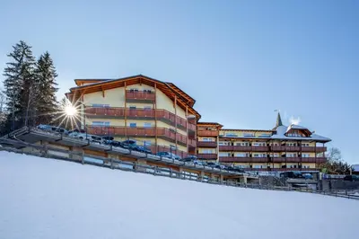 a hotel with cars parked in front of it in the snow at Parc Hotel Miramonti in Fiè