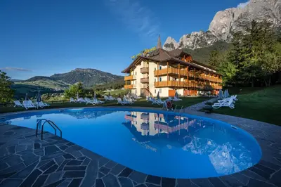 a hotel with a large swimming pool in front of a mountain at Parc Hotel Miramonti in Fiè