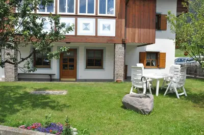 a house with a table and chairs in the yard at Casa Guido e Laura in Pozza di Fassa