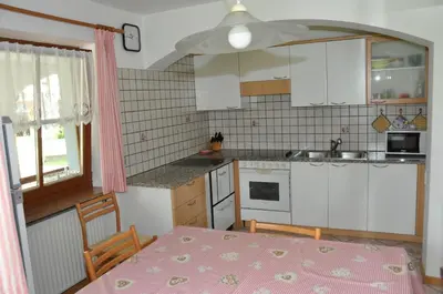 a kitchen with a table with a pink table cloth on it at Casa Guido e Laura in Pozza di Fassa