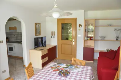 a living room with a table and a red couch at Casa Guido e Laura in Pozza di Fassa