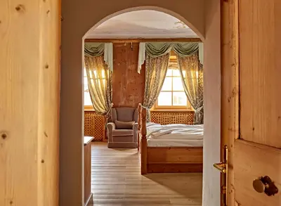a bedroom with a bed and a chair and a window at Romantic Hotel Excelsior in Cavalese