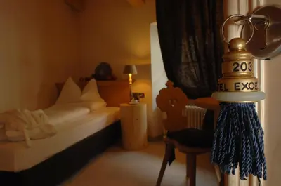 a room with a bedroom with a bed and a chair at Romantic Hotel Excelsior in Cavalese