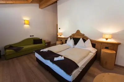 a bedroom with a bed and a green chair at Romantic Hotel Excelsior in Cavalese